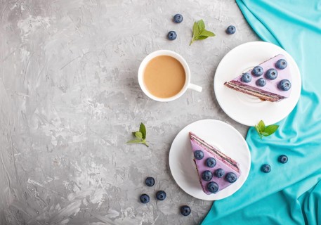Homemade cake with souffle cream and blueberry jam with cup of coffee and fresh blueberries on a