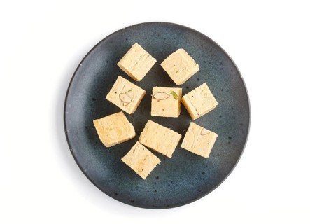 Traditional indian candy soan papdi in blue ceramic plate isolated on a white background. top view,