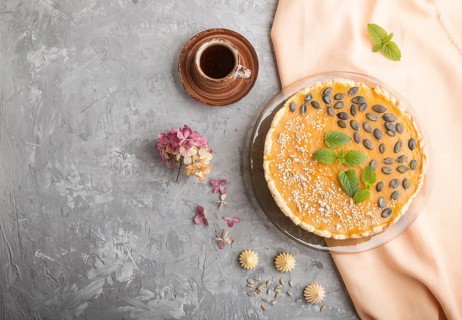 Traditional american sweet pumpkin pie decorated with mint, sesame and pumpkin seeds with cup of