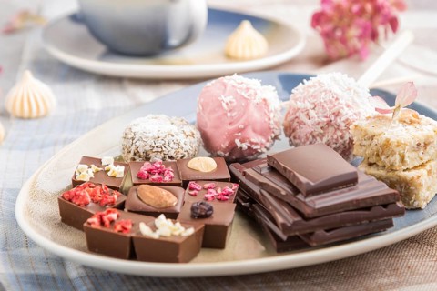A pieces of homemade chocolate with coconut candies on a blue and brown textile. side view, close