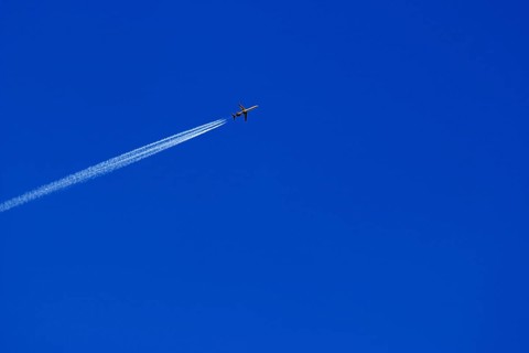A passenger plane with vapour trail high in the blue sky