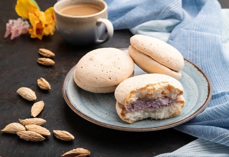 Meringues cakes with cup of coffee on a black concrete background and blue linen textile. Side