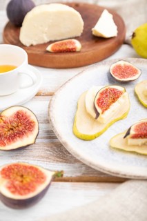 Summer appetizer with pear, cottage cheese, figs and honey on a white wooden background and linen