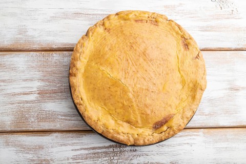 Autumn onion pie and cup of coffee on white wooden background. Top view, flat lay, close up
