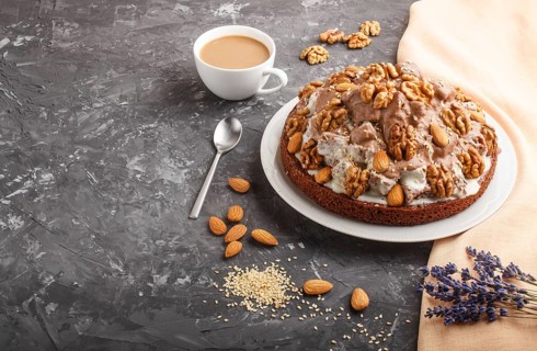 Homemade cake with milk cream, cocoa, almond, hazelnut on a black concrete background with orange