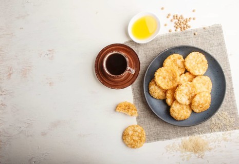 Traditional japanese rice chips cookies with honey and soy sauce on a blue ceramic plate and a cup