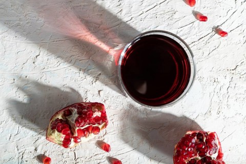 Glass of pomegranate juice on a white concrete background. Hard light, contrast. Top view, close