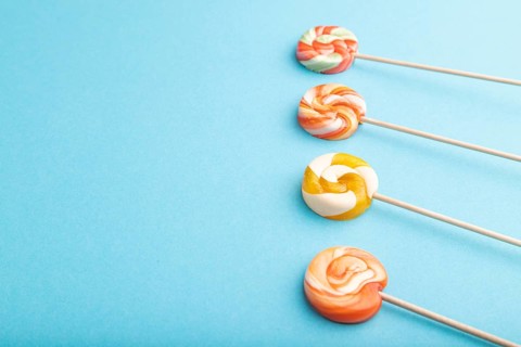 Four lollipop candies on blue pastel background. copy space, side view