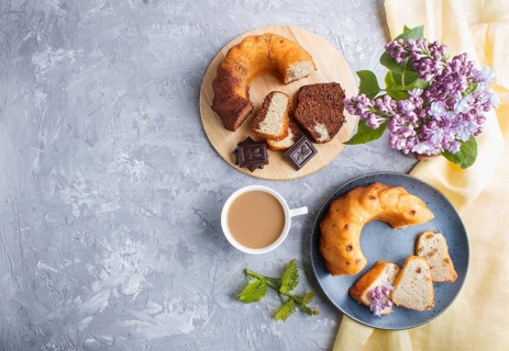 Cakes with raisins and chocolate and a cup of coffee. lilac flowers on a gray concrete background,