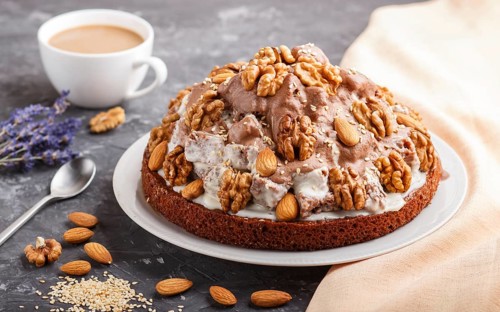 Homemade cake with milk cream, cocoa, almond, hazelnut on a black concrete background with orange