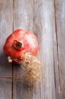 Ripe garnet with a branch on a rustic wooden background