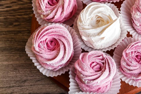 Pink and white homemade marshmallows (zephyr) on a round wooden board on a gray wooden background.