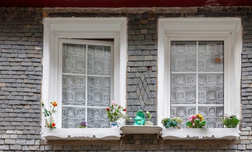 Slate-clad house facade, two windows and decoration made of artificial flowers, historic old town,