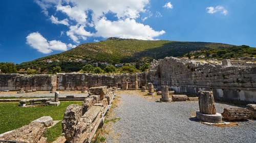 Ruins of an ancient site with broken columns and stones under a blue sky, Sanctuary of Asclepius,