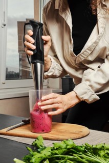 Unrecognizable woman making purple smoothie with banana and black currant