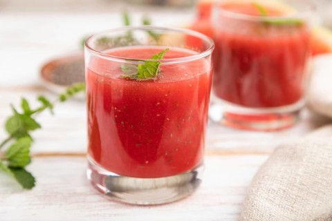 Watermelon juice with chia seeds and mint in glass on a white wooden background with linen textile.