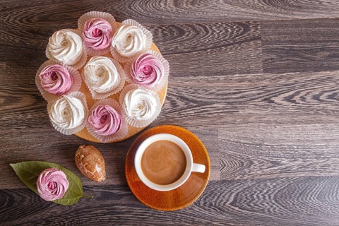 Pink and white homemade marshmallows (zephyr) with cup of coffee on a gray wooden background. top