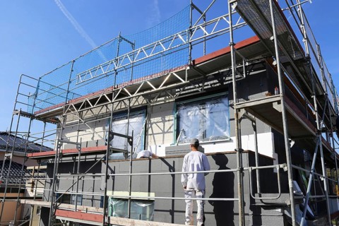 Construction workers insulate a house facade