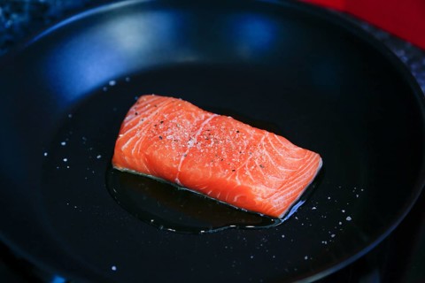 Preparation of Dreisam salmon with wild rice, raw salmon fillet in a pan, frying in oil, southern
