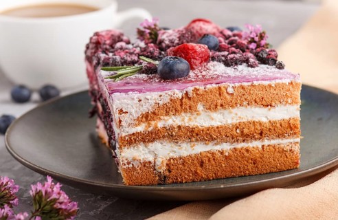 Berry cake with milk cream and blueberry jam on blue ceramic plate with cup of coffee and fresh