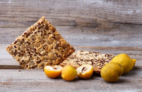 Biscuits with flax, sesame and sunflower seeds and yellow quince fruit on a rustic wooden