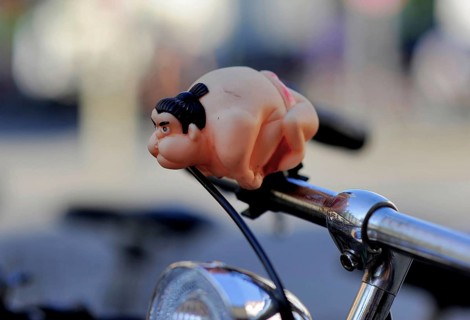 A sumo wrestler attached to the handlebars of a bicycle as a bicycle horn or bell