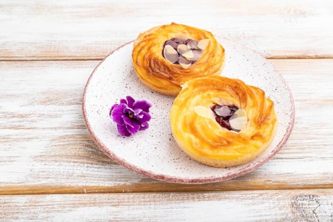 Small cheesecakes with jam and almonds on a white wooden background. Side view, close up