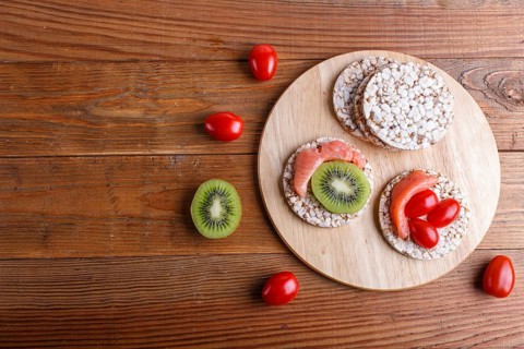 Rice cakes with salmon, kiwi and cherry tomatoes on wooden background. top view, copy space