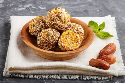 Energy ball cakes with dried apricots, sesame, linen, walnuts and dates with green mint leaves in a