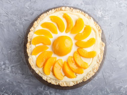 Round peach cheesecake on a gray concrete background. top view, flat lay, close up