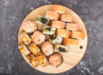 Mixed japanese maki sushi rolls set on black concrete background. Top view, close up, flat lay