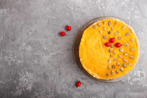 Traditional american sweet pumpkin pie decorated with hawthorn red berries and pumpkin seeds on a