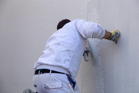 Plasterers plaster the facade of a new building (Mutterstadt development area,
