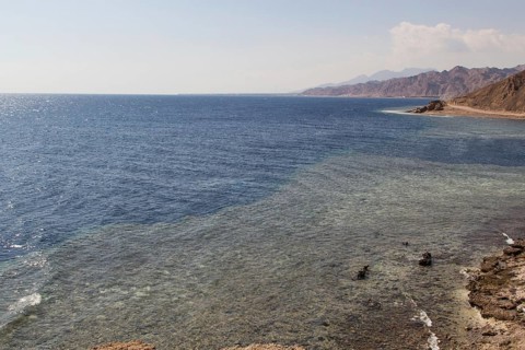 The coastline of the Red Sea with small resorts and the mountains in the background. Coral reef