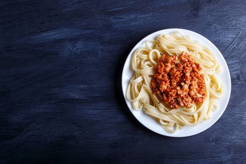 Fettuccine bolognese pasta with minced meat on black wooden background. top view, copy space