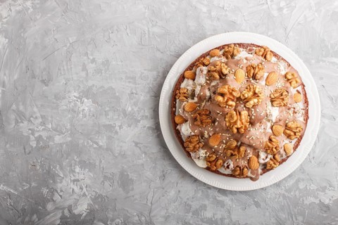 Homemade cake with milk cream, cocoa, almond, hazelnut on a gray concrete background with orange