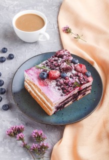 Berry cake with milk cream and blueberry jam on blue ceramic plate with cup of coffee and fresh