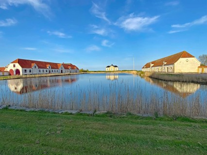 Large houses and the teahouse at Valdemars Slot are reflected in the calm water, Valdemars Slot,