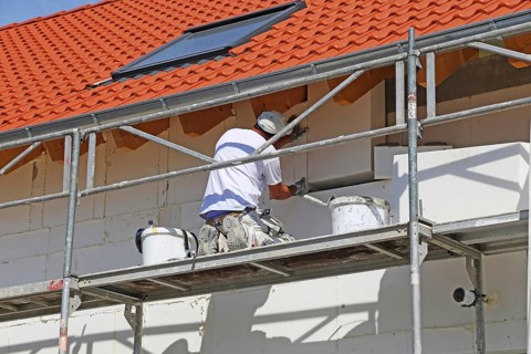 Construction workers insulate a house facade