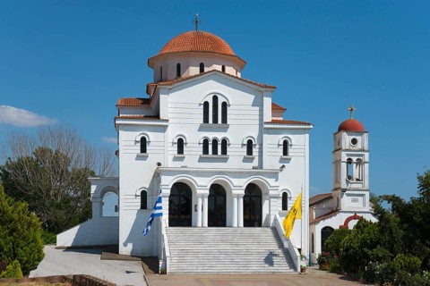 A whitewashed church with a red roof and a dome under a clear blue sky, Greek Orthodox Church of