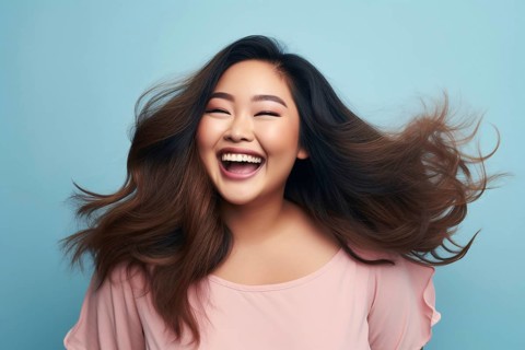 Lauging happy plus size curvy Asian woman in front of blue studio background. KI generiert,