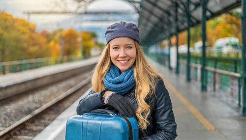 AI generated, A young blonde woman wants to travel and waits for the train at the station, 20, 25,