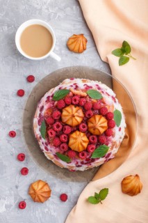 Homemade jelly cake with milk, cookies and raspberry on a gray concrete background with cup of