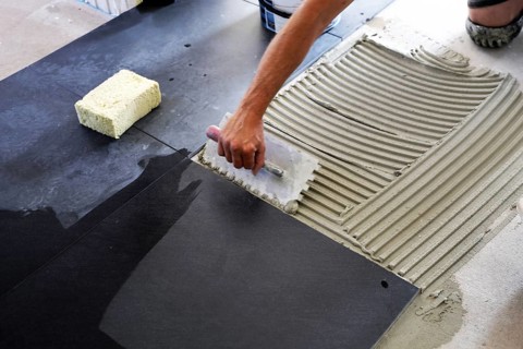 Tiler lays modern large floor tiles in a bathroom