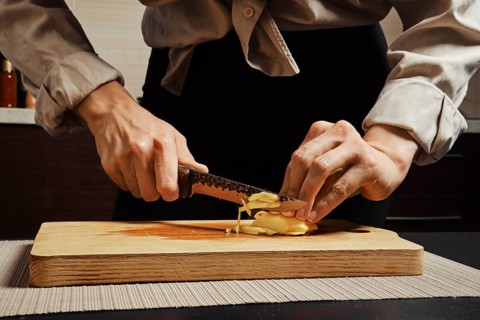 Unrecognizable woman slicing peeled ginger root into thin strips