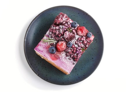 Berry cake with milk cream and blueberry jam on blue ceramic plate isolated on white background.
