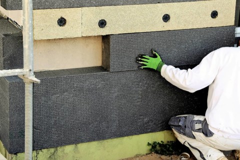 Construction workers insulate a house facade