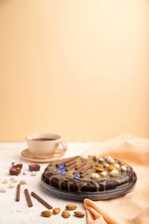 Homemade chocolate brownie cake with caramel cream and almonds with cup of coffee on a white and