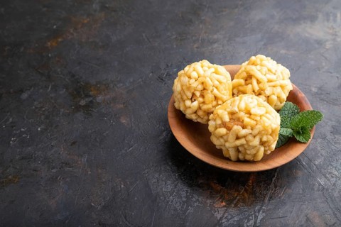 Traditional Tatar candy chak-chak made of dough and honey in wooden plate on a black concrete