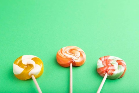 Three lollipop candies on green pastel background. copy space, top view, flat lay
